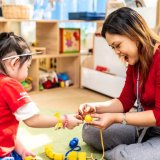 Teacher playing toys with girl